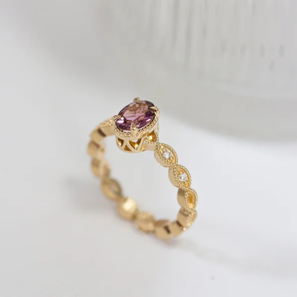 Ażurowy, złoty pierścionek z różowym, owalnym turmalinem z diamentami na obrączce