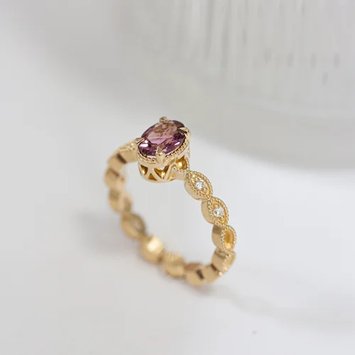 Ażurowy, złoty pierścionek z różowym, owalnym turmalinem z diamentami na obrączce